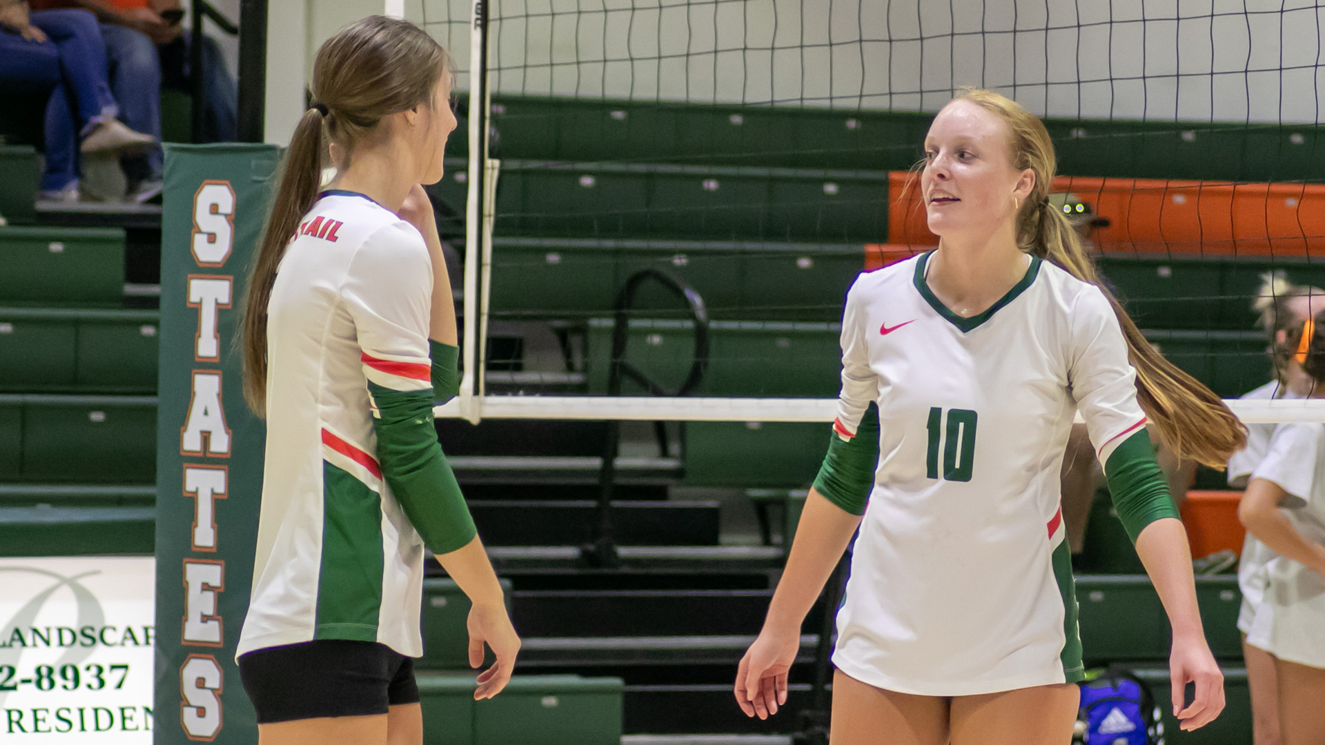 Faith Shull, left, and Hannah Saucerman, right, talk with each other in front of the net prior or a game.
